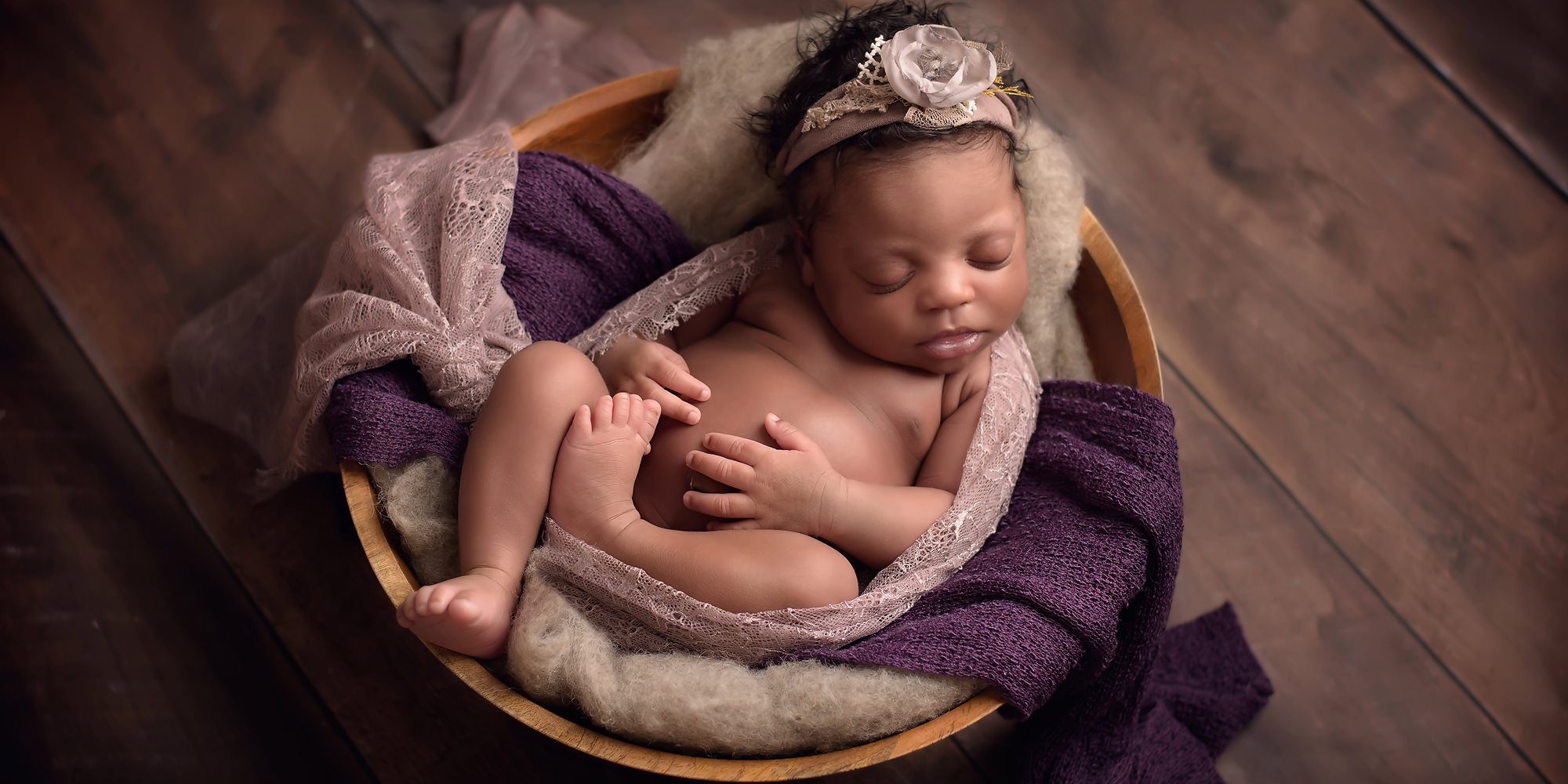 newborn baby girl in purple bowl